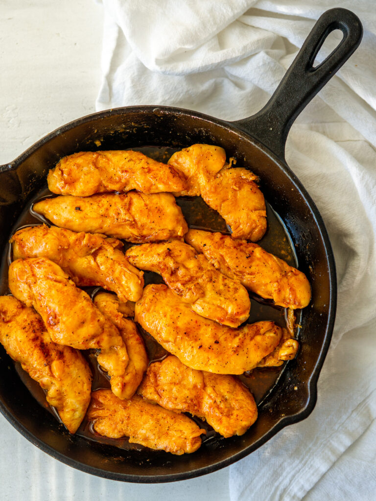 Above view of honey sriracha chicken tenders in a large cast iron skillet