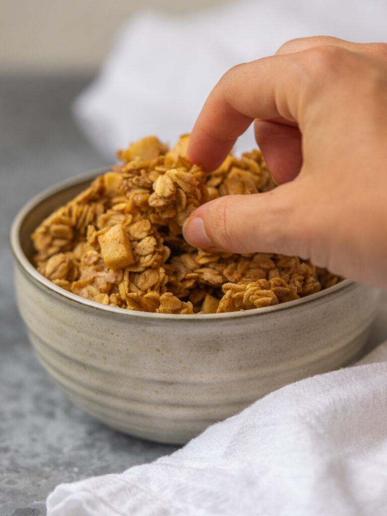 a photo of a hand grabbing granola from a bowl