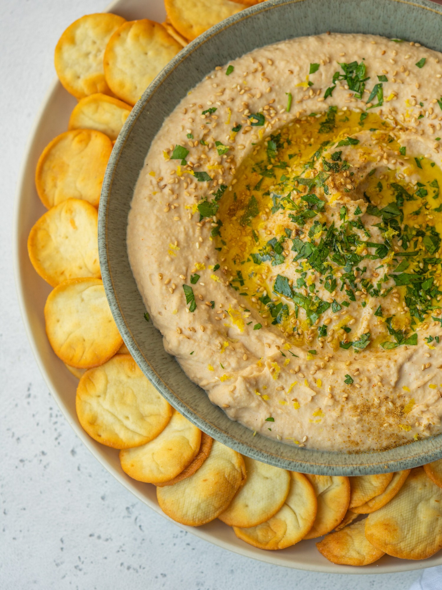 Above view of creamy white bean hummus in a bowl served with pita crackers