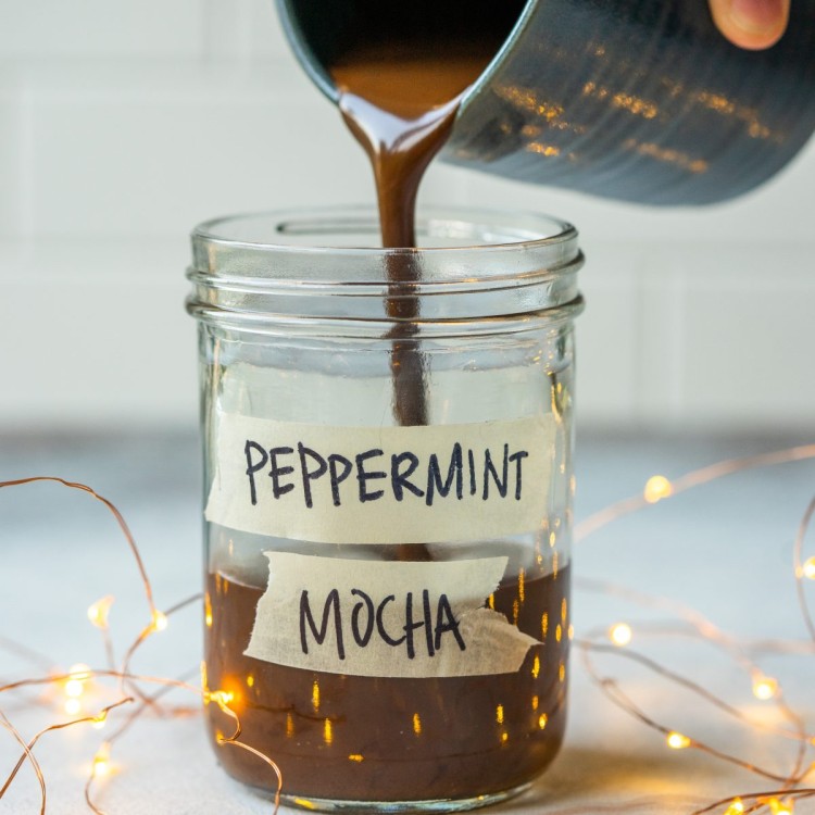 Side view of a peppermint mocha syrup pouring into a glass jar