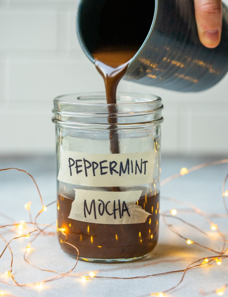 Side view of a peppermint mocha syrup pouring into a glass jar