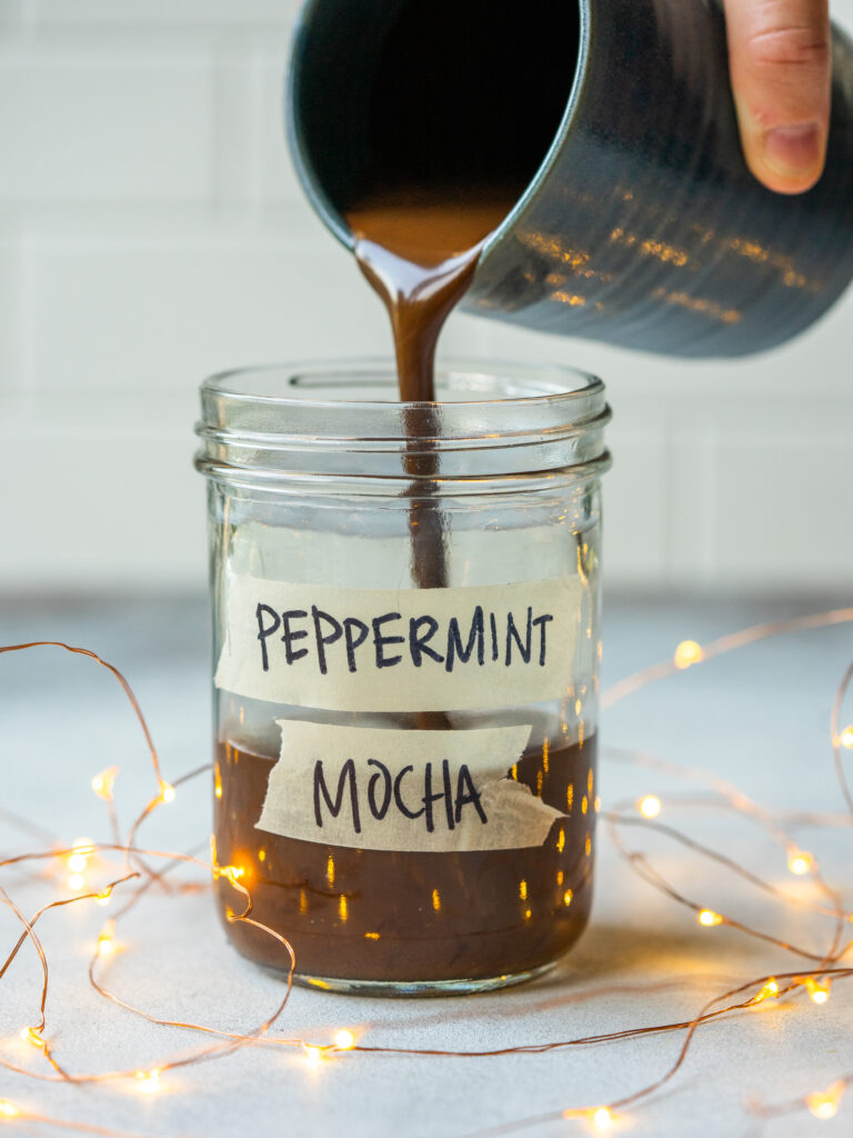 side view of a peppermint mocha syrup being poured into a glass jar for storage