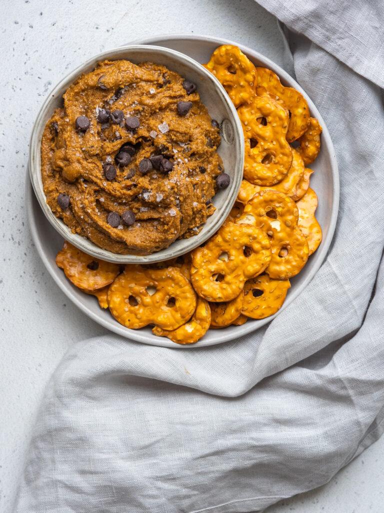 Above view of a chocolate chip cookie dough dip in a serving bowl with pretzel thins on the side