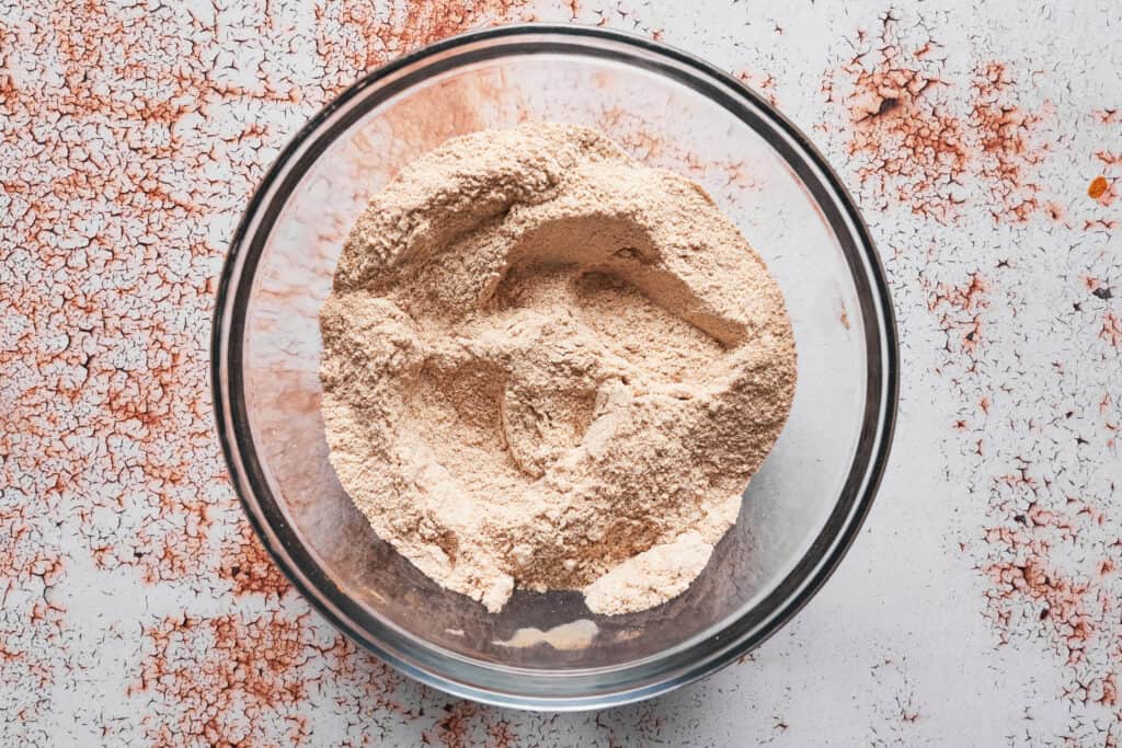 whole wheat flour, pumpkin pie spice, baking soda, baking powder, and salt being mixed together 