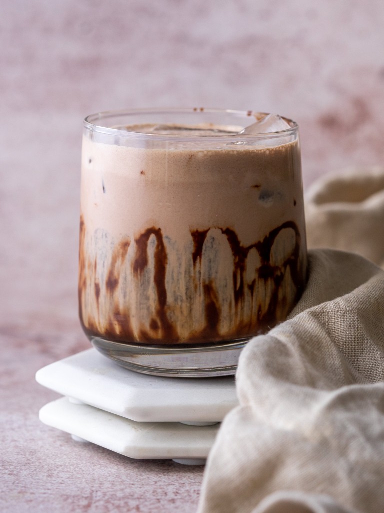 Side view of an iced peppermint mocha recipe in a glass cup
