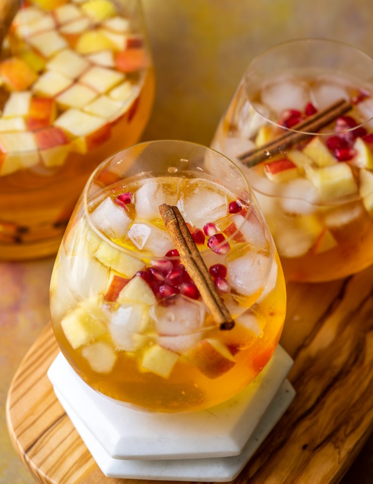 Apple cider sangria recipe in serving glasses topped with cinnamon and pomegranate seeds