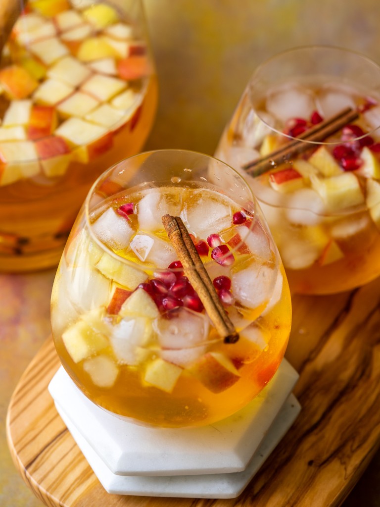 Apple cider sangria recipe in serving glasses topped with cinnamon and pomegranate seeds