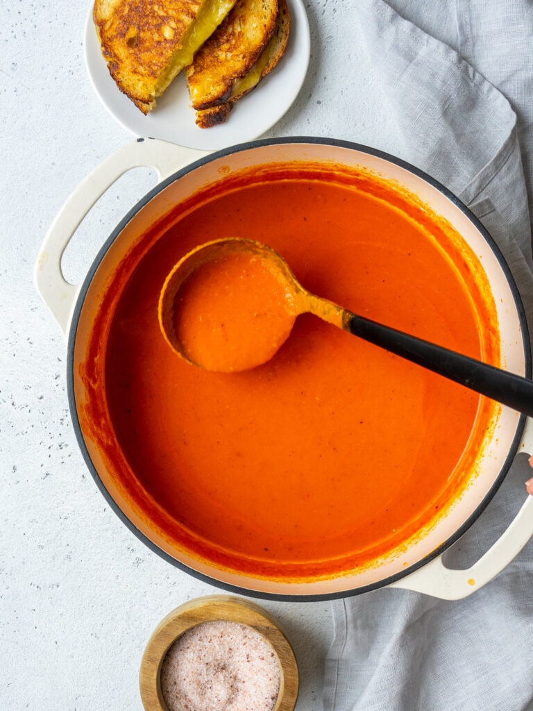 ladle grabbing a serving of roasted red pepper soup
