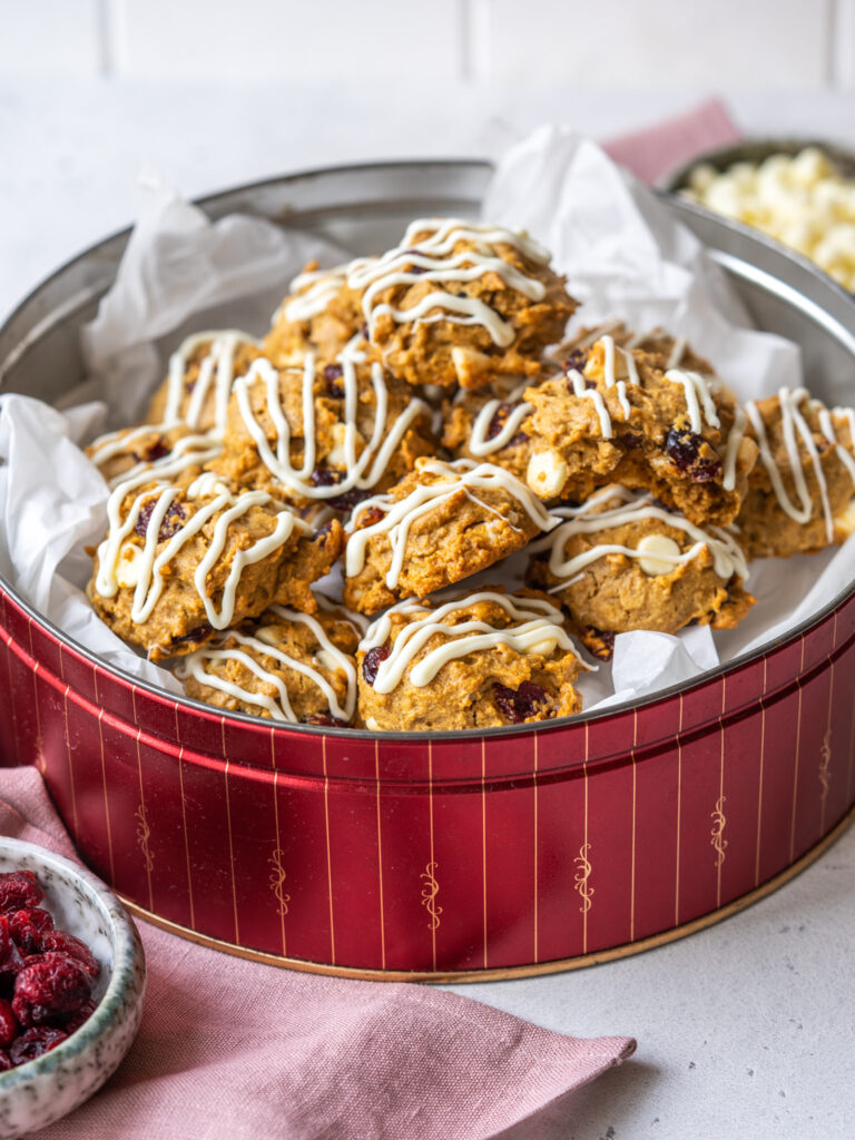 side view of healthy white chocolate cranberry oatmeal cookies in a tin