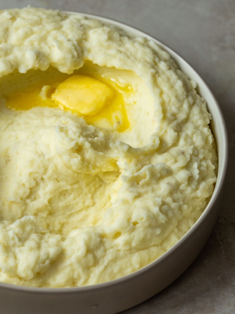 creamy mashed potatoes in a serving bowl with a pad of melted butter
