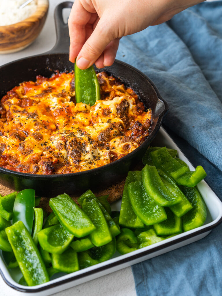 green bell pepper dipping into cast iron skillet