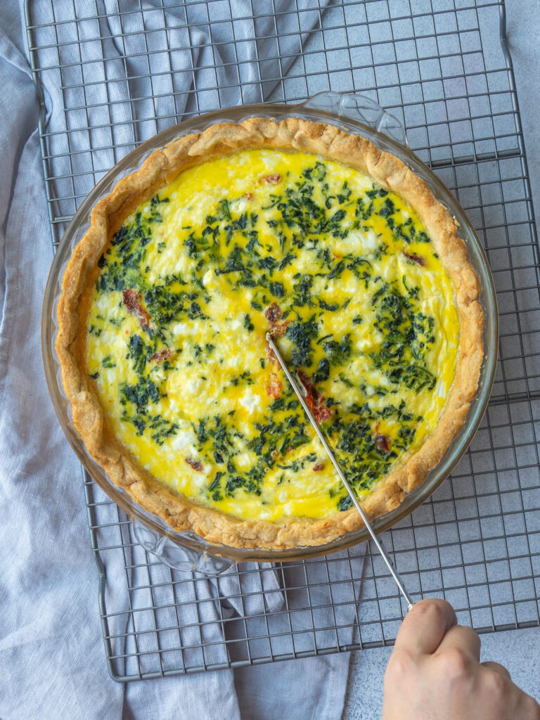 above view of cooked veggie quiche with a knife slicing it