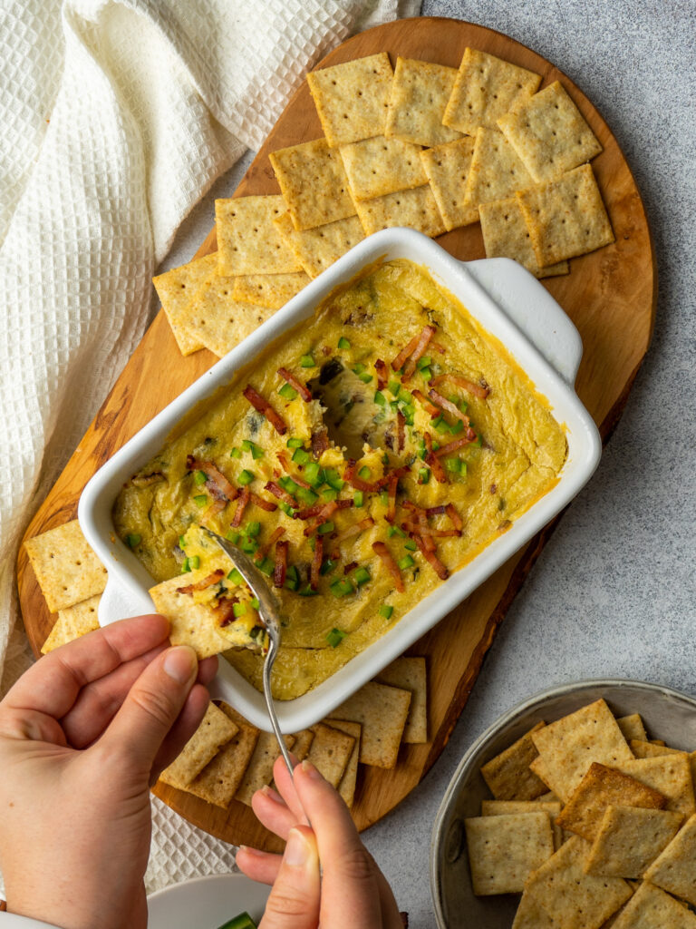 Above view of a spoon scooping a spoonful or dairy free jalapeno popper dip onto a cracker