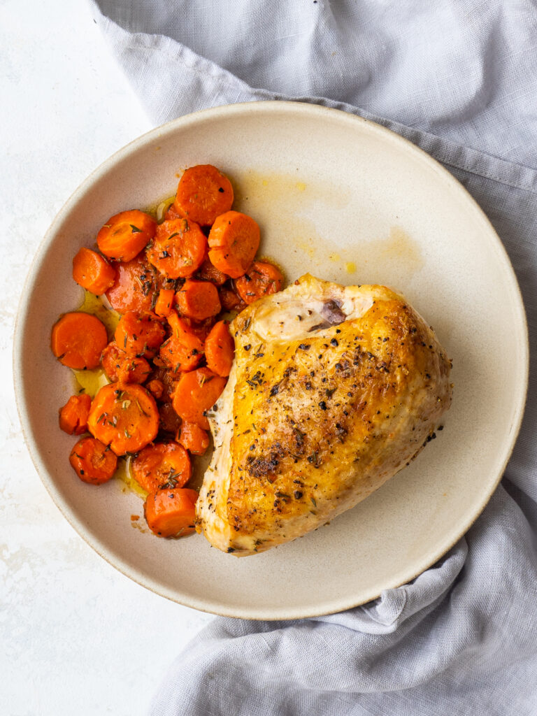 overhead view of split chicken breast on a plate with carrots