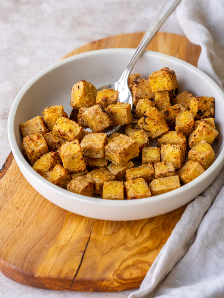 Three quarter view of air fryer fryer tofu cubes in a bowl with a spoon