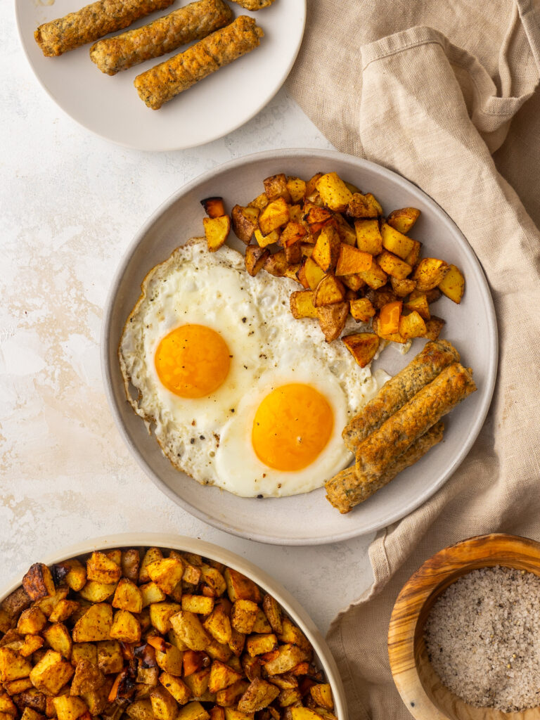 overhead view of air fryer breakfast recipe with potatoes, sausage and eggs