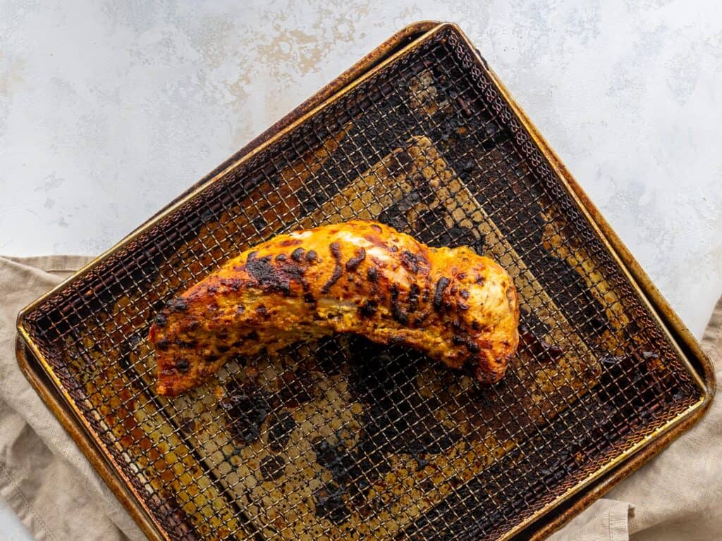 one cooked pork tenderloin on an air fryer basket
