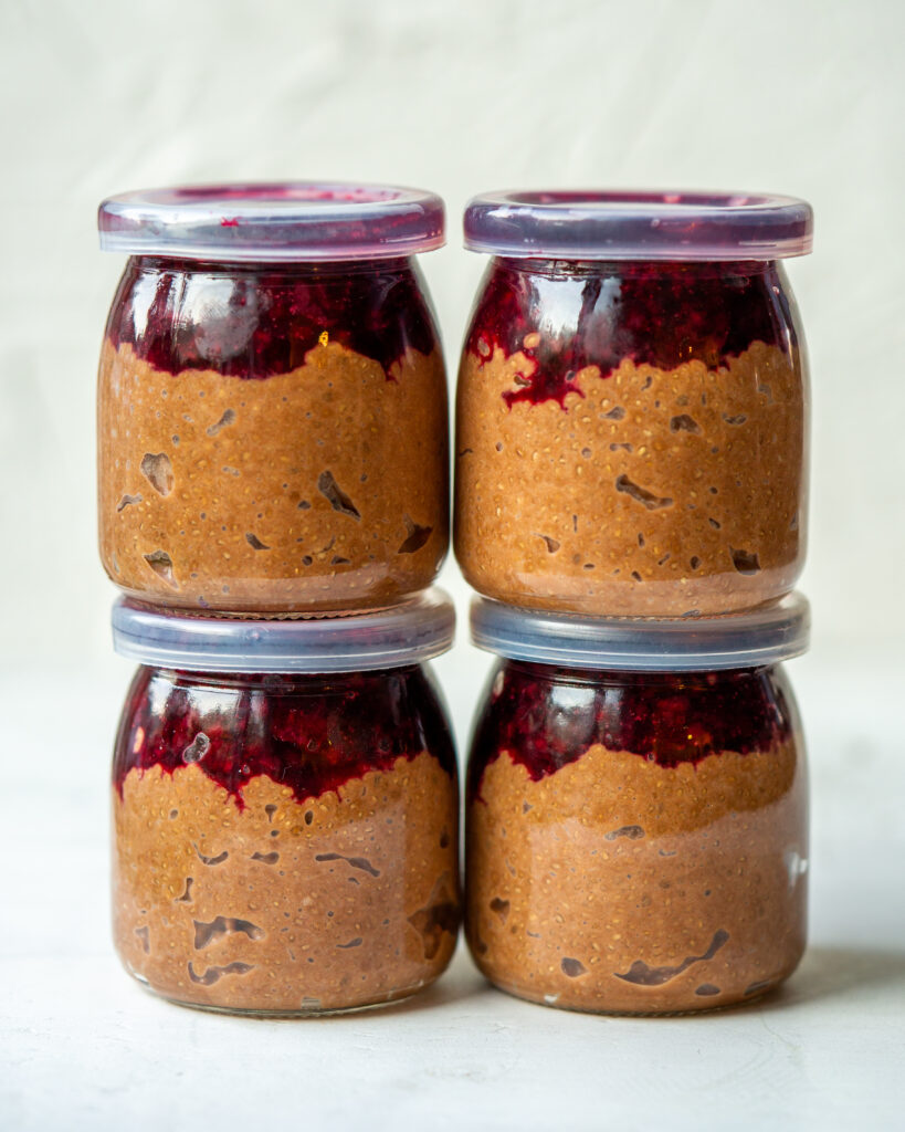Side view of chocolate chia seed pudding with cherry compote in small single serve jars.