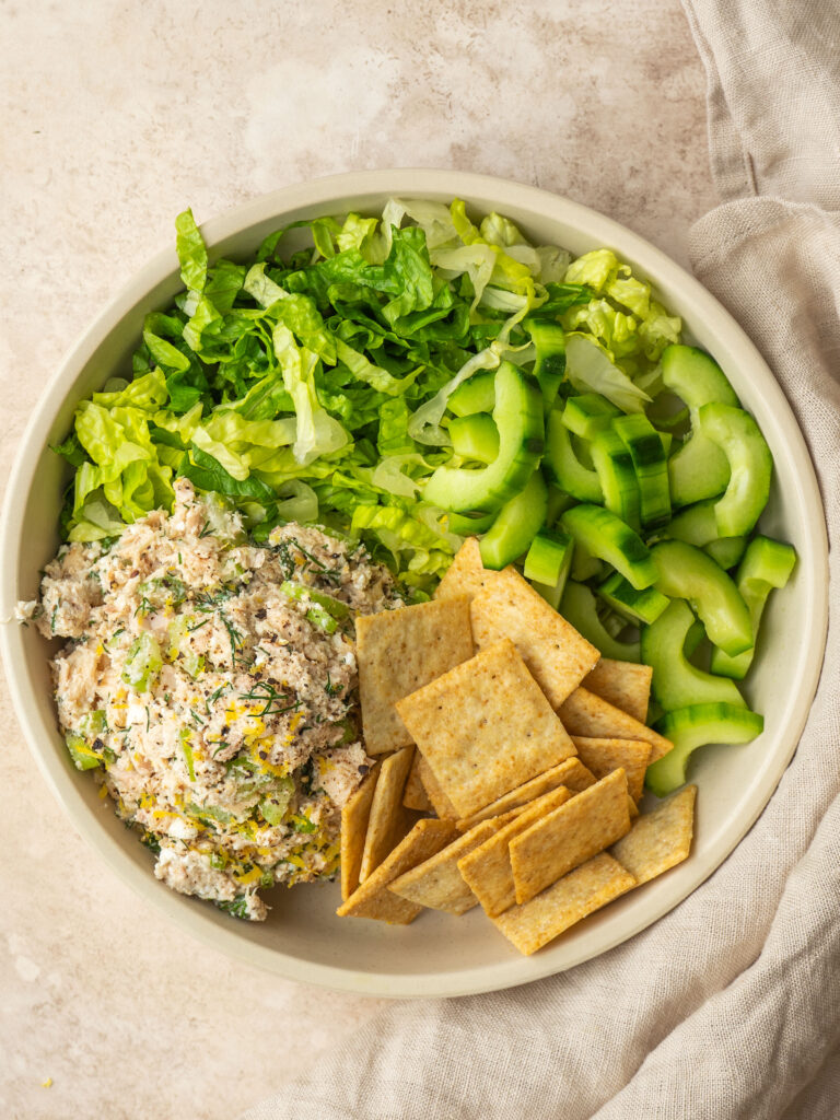 Above view of no mayo tuna salad served on romaine lettuce with crackers and cucumbers