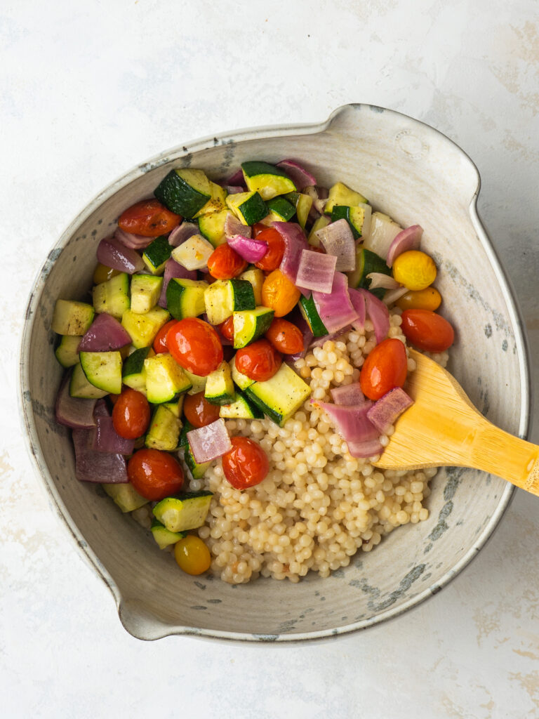 Mixing bowl with cooked Israeli couscous and roasted vegetables