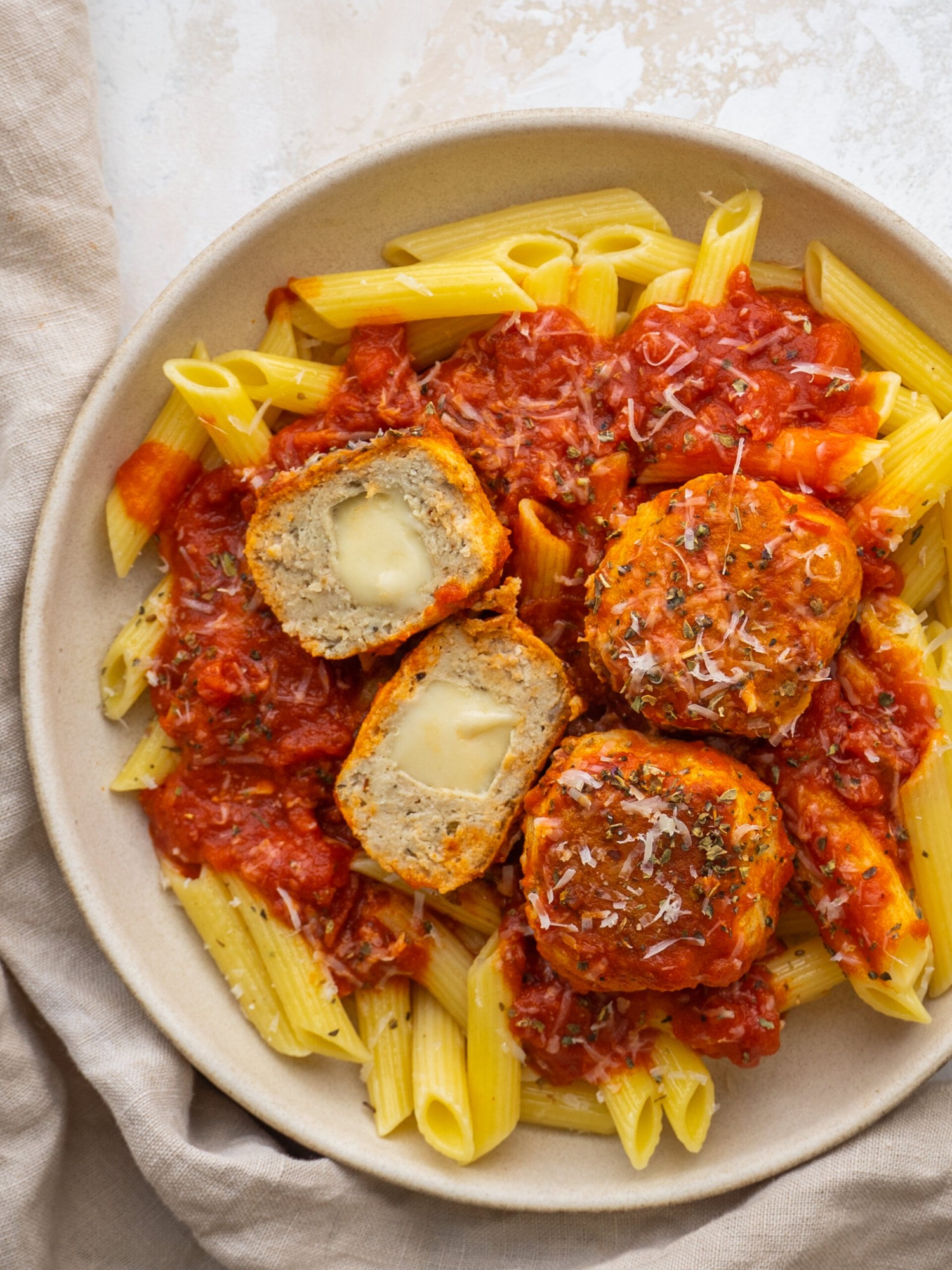 Above view of mozzarella stuffed meatballs on a plate with marinara sauce and pasta