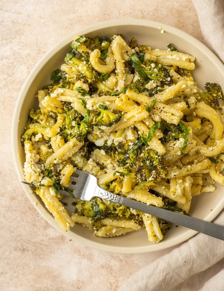 Broccoli pasta made with creamy feta in a small serving bowl with a fork in it