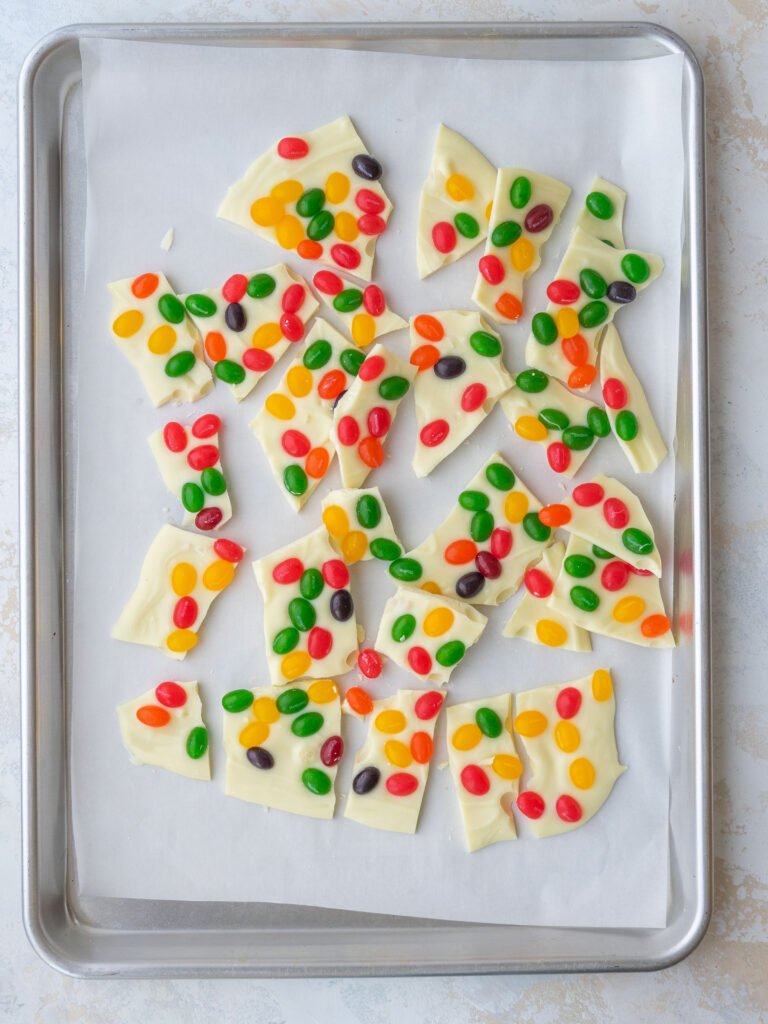 Above view of Easter jelly bean bark pieces on a sheet pan