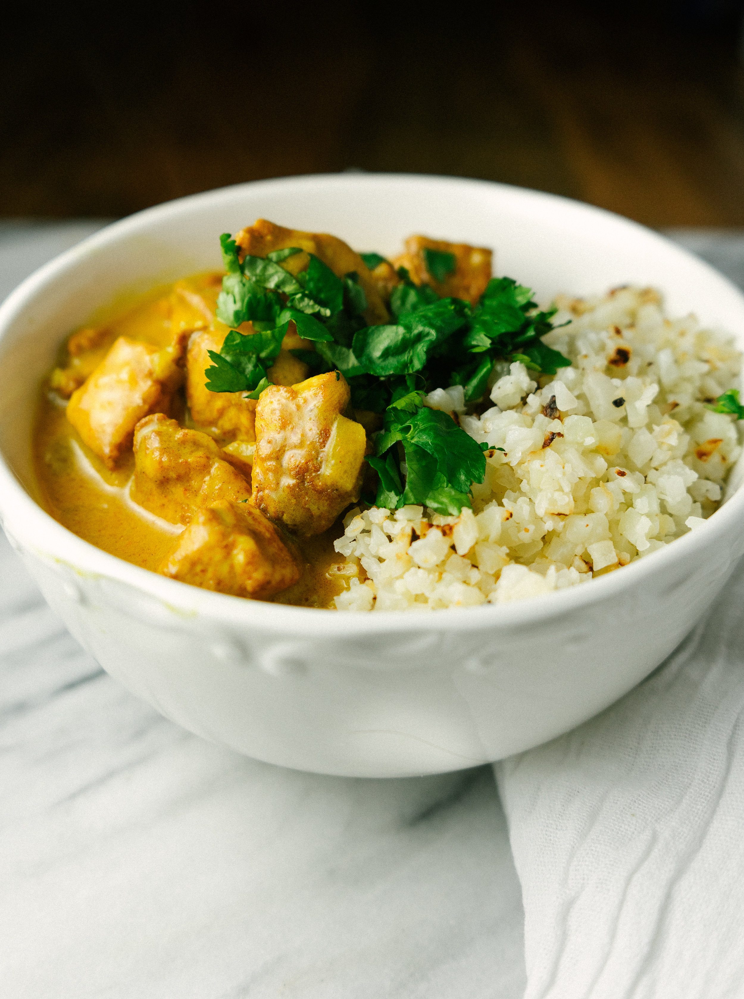 Three quarter view of healthy butter chicken in a bowl with cauliflower rice