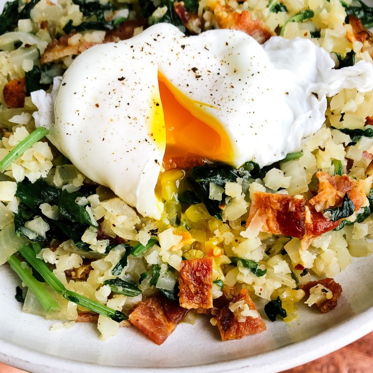 Cauliflower rice breakfast stir fry on a plate with a poached egg on top