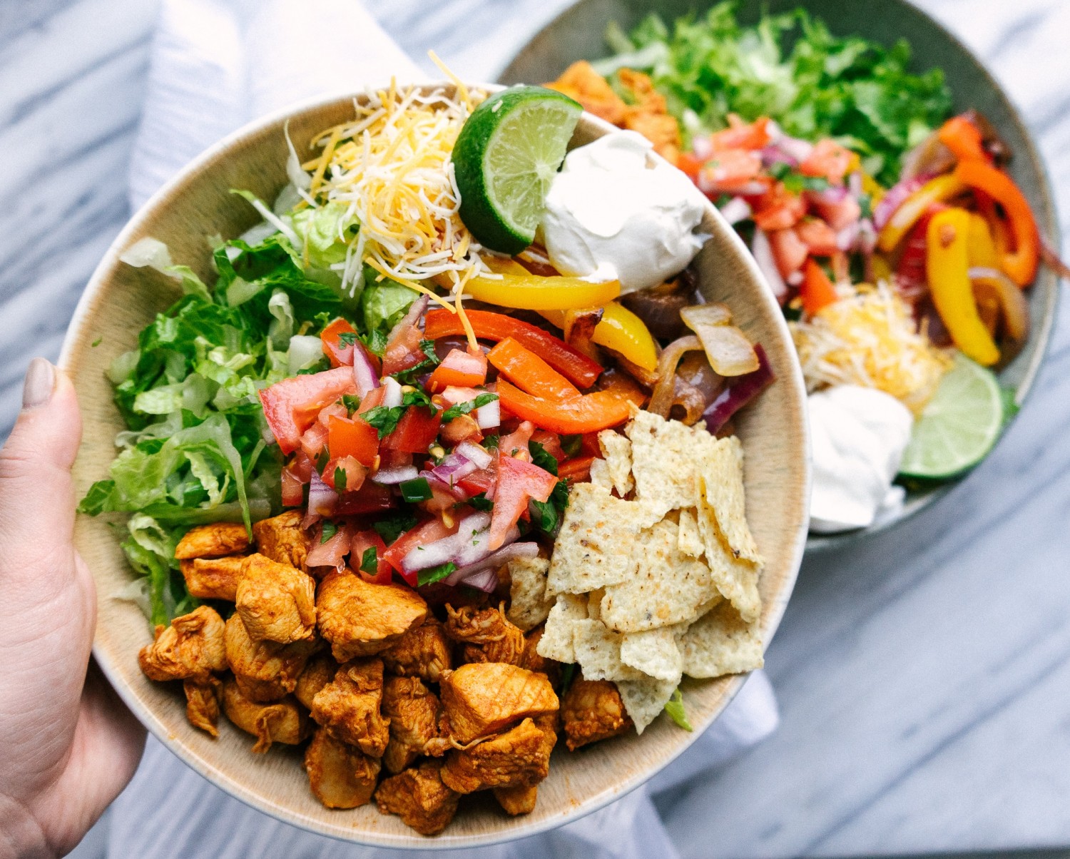 Above view of chicken fajita salad in a serving bowl with lots of toppings