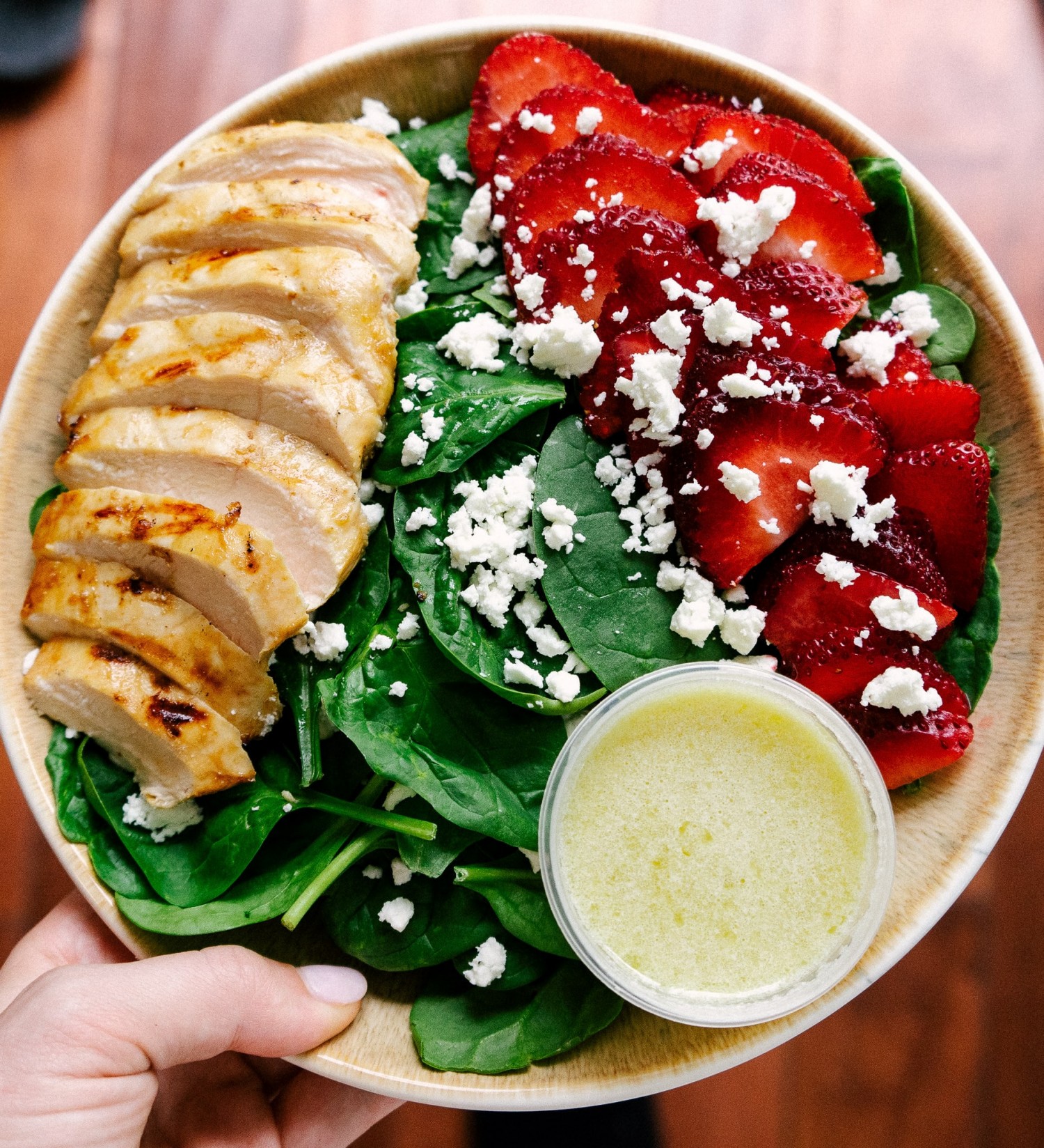 Above view of sliced ginger lime chicken on a salad with spinach and straberries