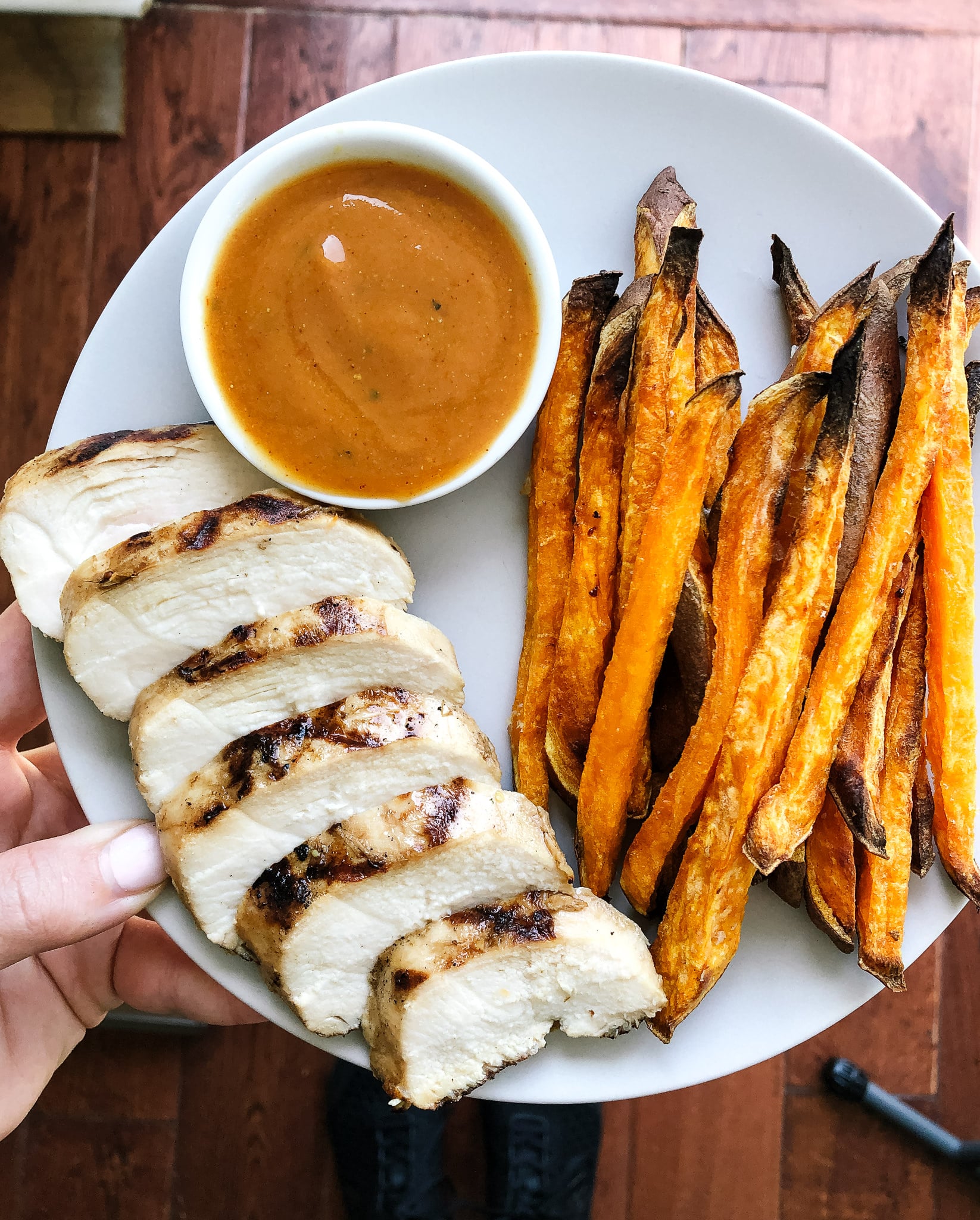 Above view of sliced ginger lime chicken on a plate with sweet potato fries and carolina gold bbq sauce