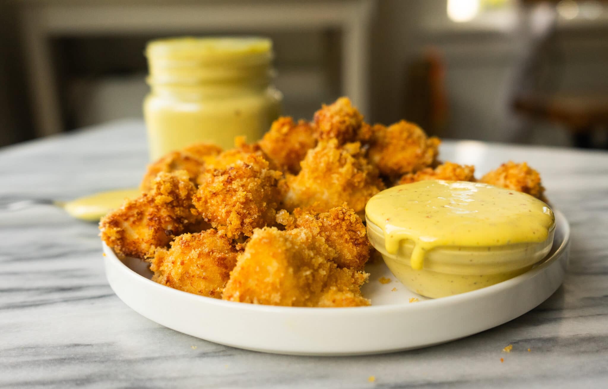 Side view of chicken nuggets on a plate with a dish of creamy honey mustard sauce