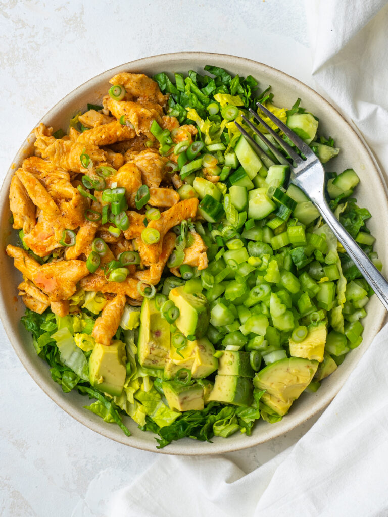 Close up above view of a chipped green salad with buffalo chicken