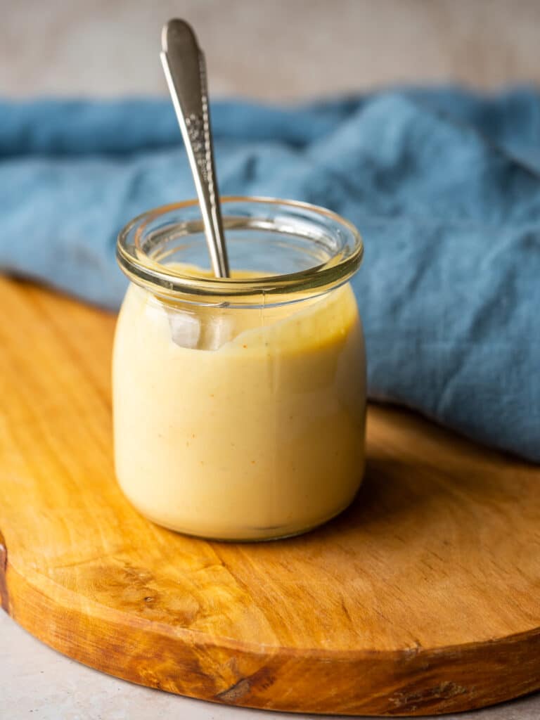 Side view of a homemade dairy free aioli in a glass jar