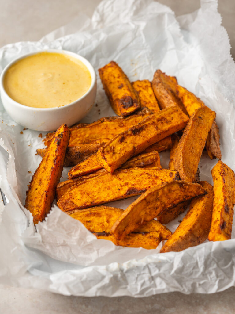 Three quarter view of Air Fryer Sweet Potato Wedges on a serving platter with roasted garlic aioli dip