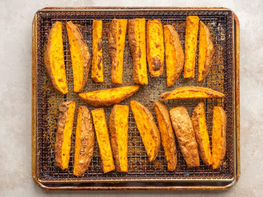 Air fried seasoned sweet potato wedges on an air fryer tray