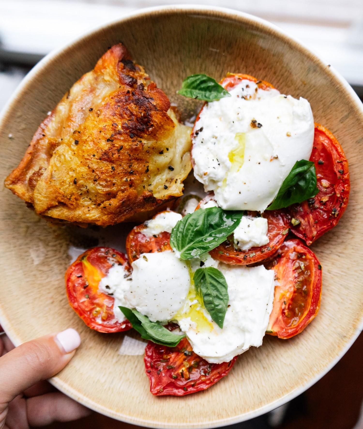 Above view of tomato and burrata salad on a plate with a crispy grilled chicken thigh