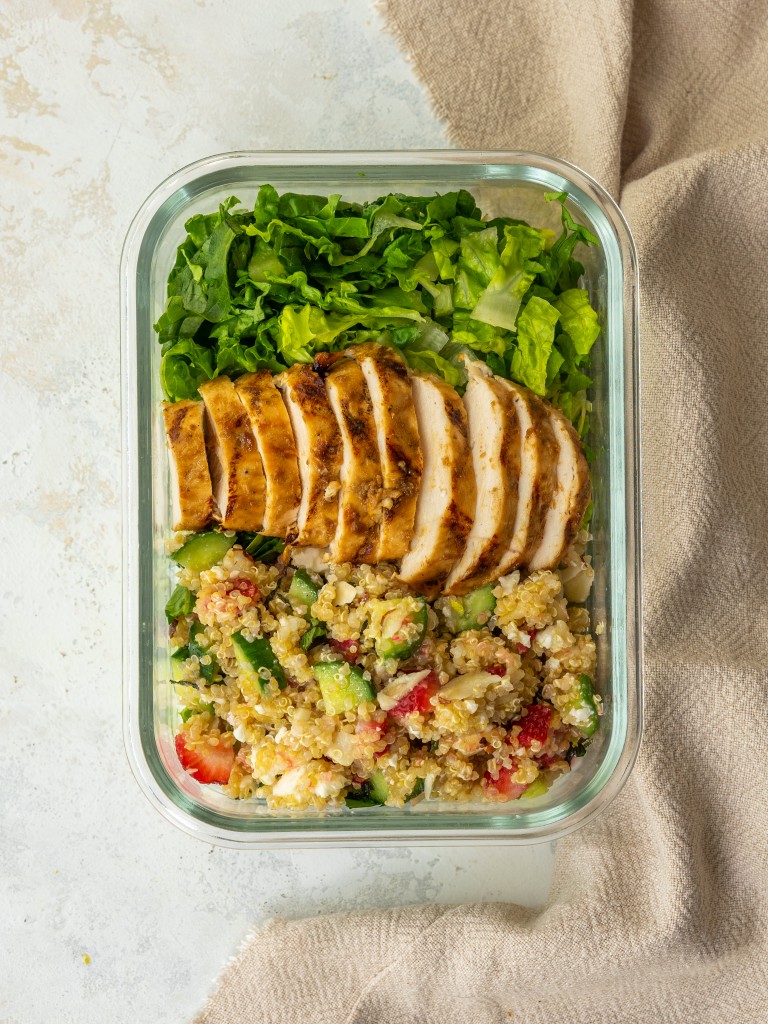 Above view of sliced balsamic chicken served on a green salad with quinoa