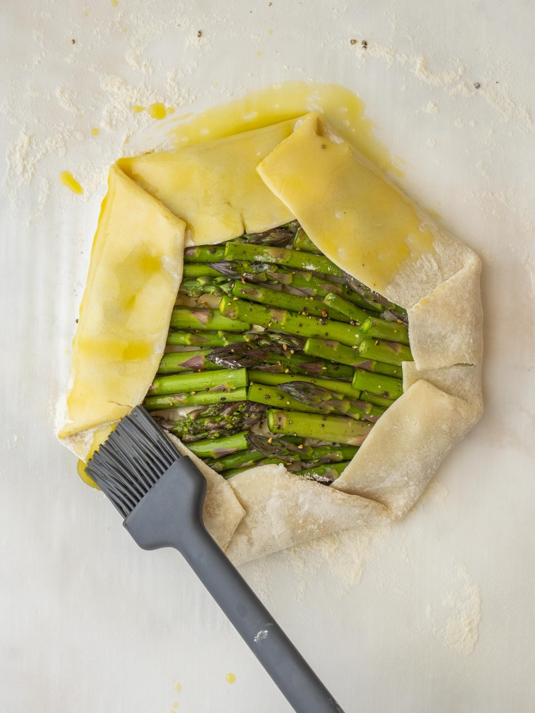Above view of a food brush brushing olive oil onto galette crust