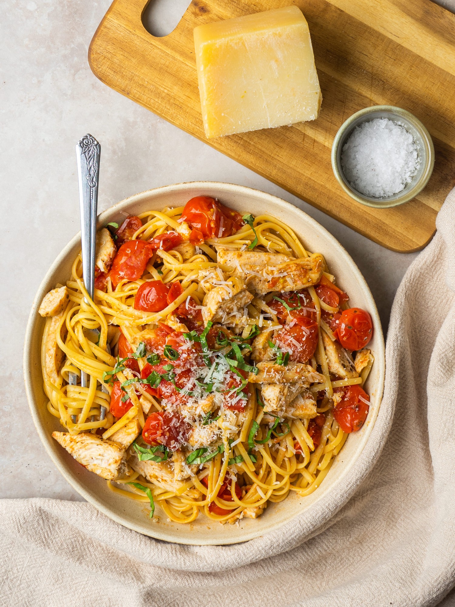 Above view of cherry tomato sauce in a serving bowl with linguine and chicken
