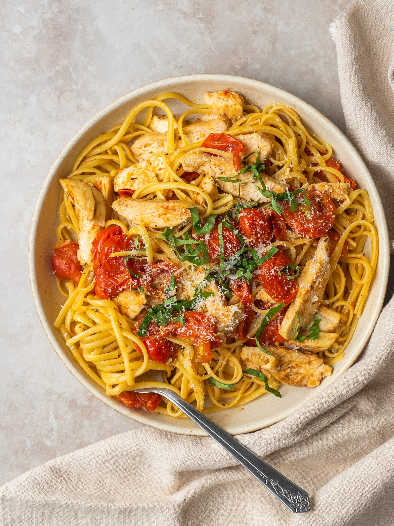 Above view of a serving bowl with cherry tomato pasta and chicken