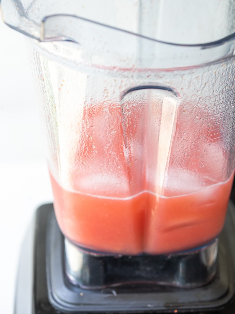 Three quarter view of ice cubes in a blender with blended frose recipe