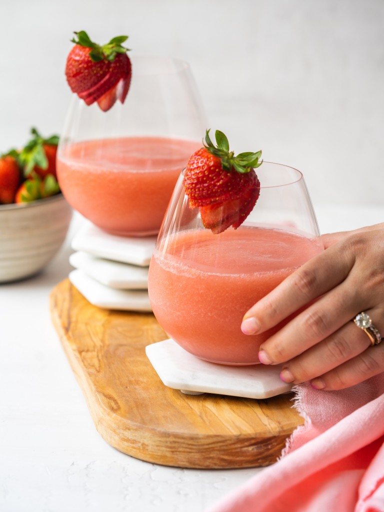 Side view of a hand grabbing a glass of frose