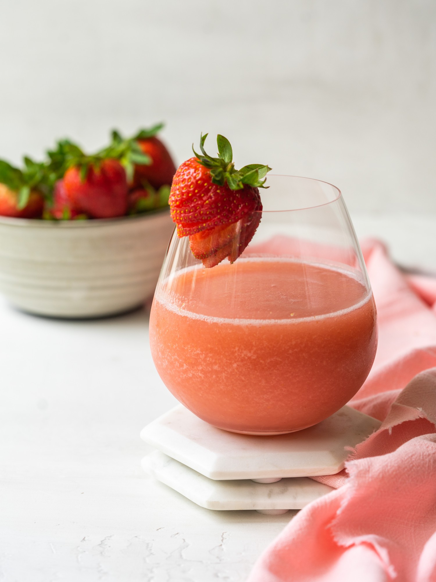 Side view of a homemade frose recipe in a wine galss with a strawberry garnish