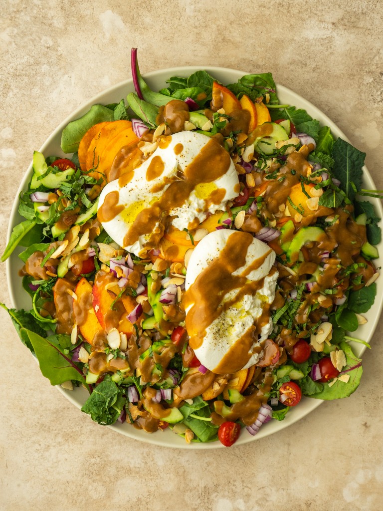 Peach burrata salad topped with creamy balsamic dressing