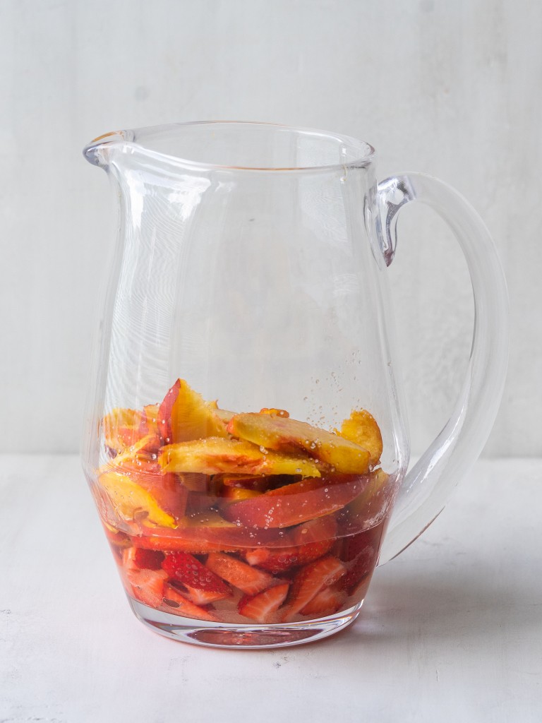 Side view of strawberries and peaches in a pitcher