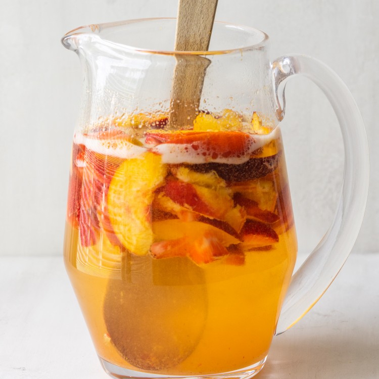 Side view of white wine peach sangria in a pitcher