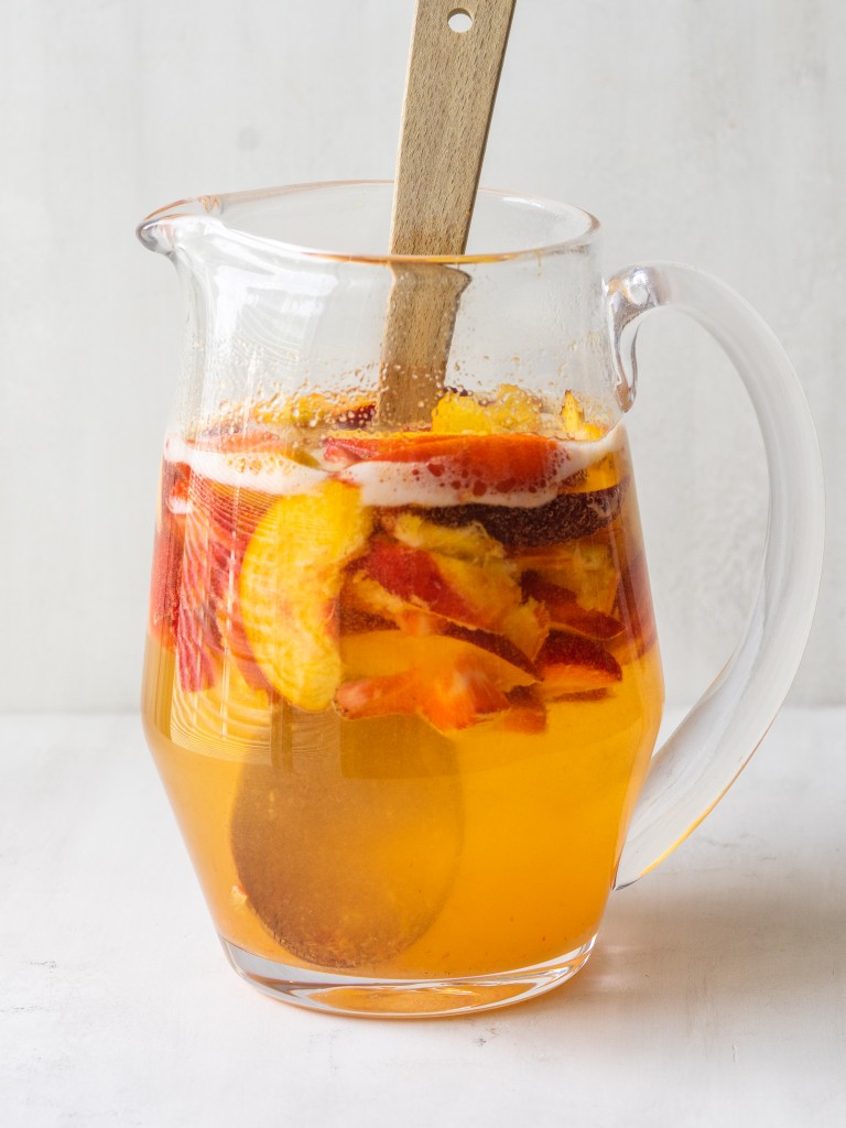 Side view of white wine peach sangria in a pitcher