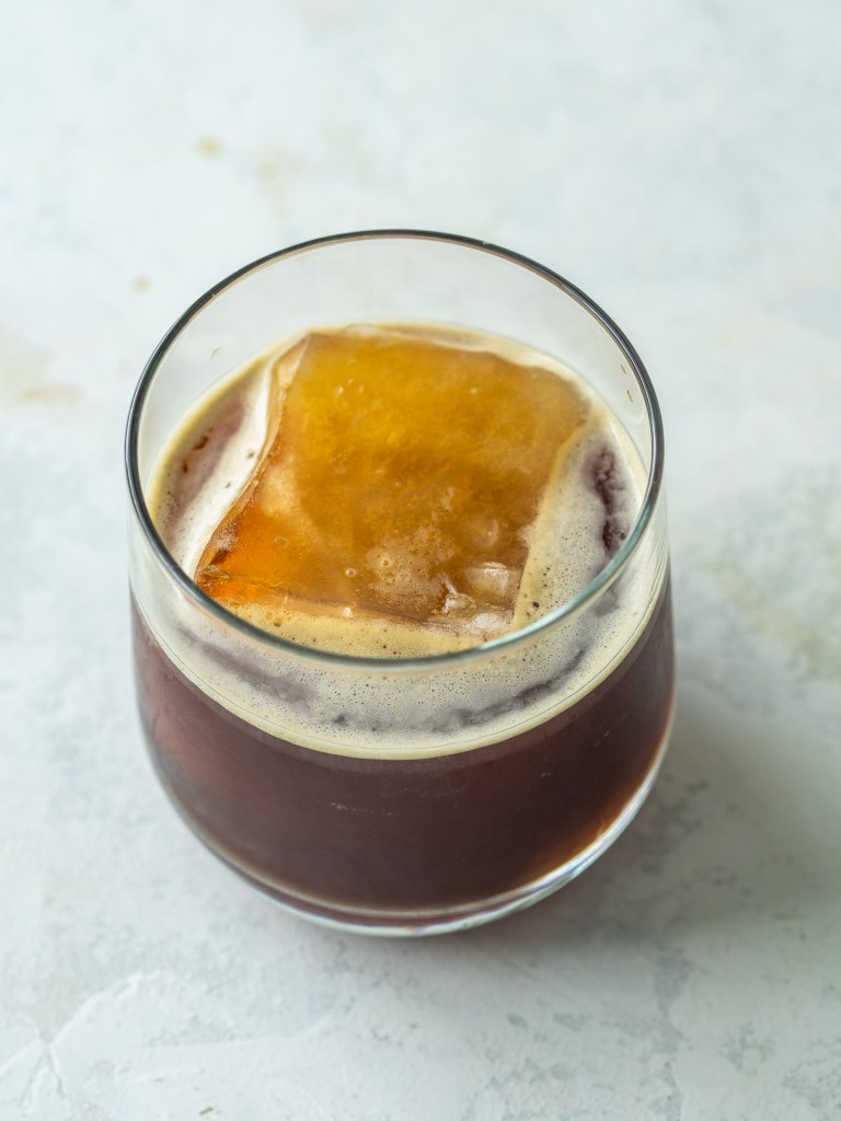 Above view of iced shaken espresso in a cup with a large ice cube